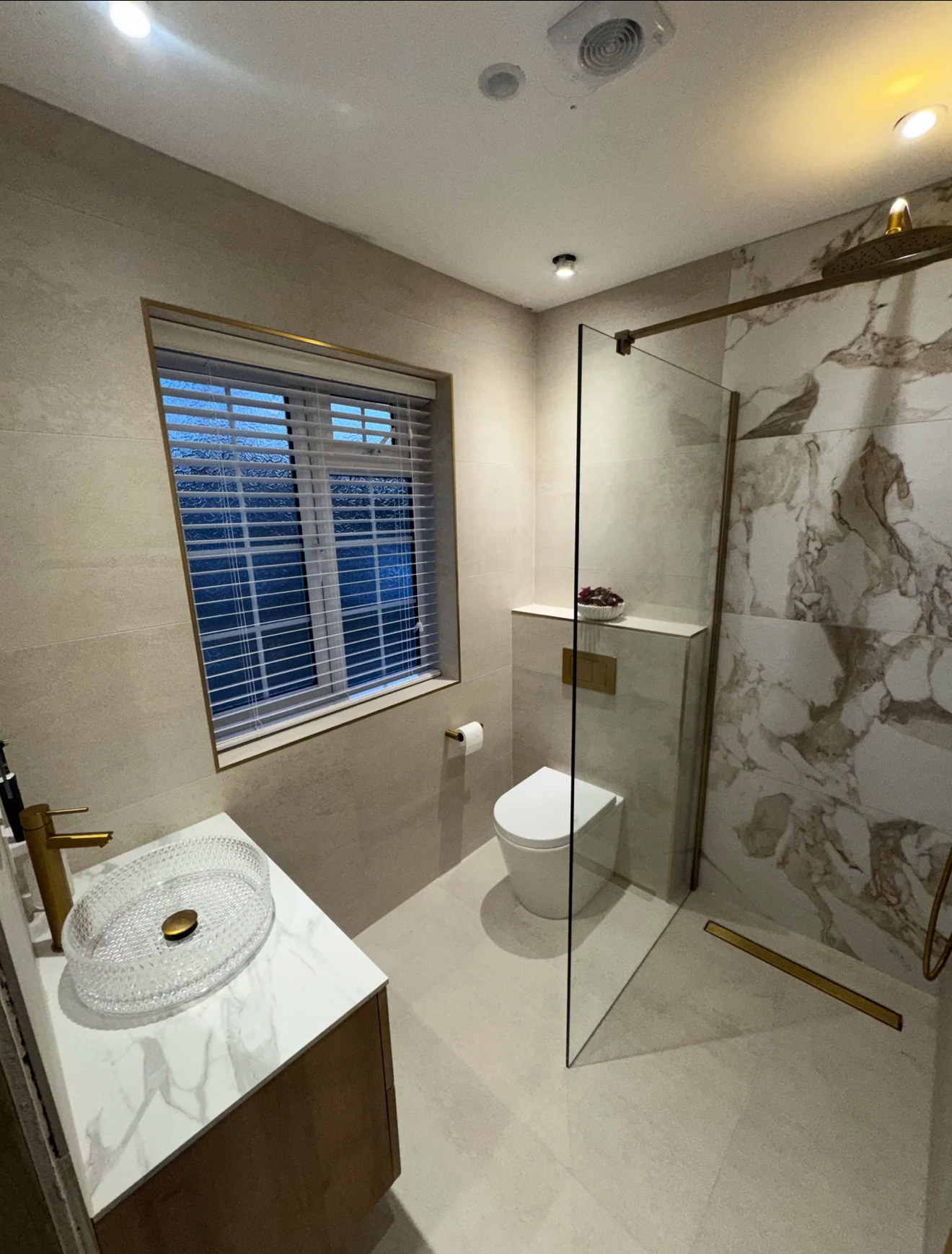 Elegant marble bathroom with clear glass walk-in shower, vessel basin, brass tap and window shutters — bathroom installation in Reading, Berkshire