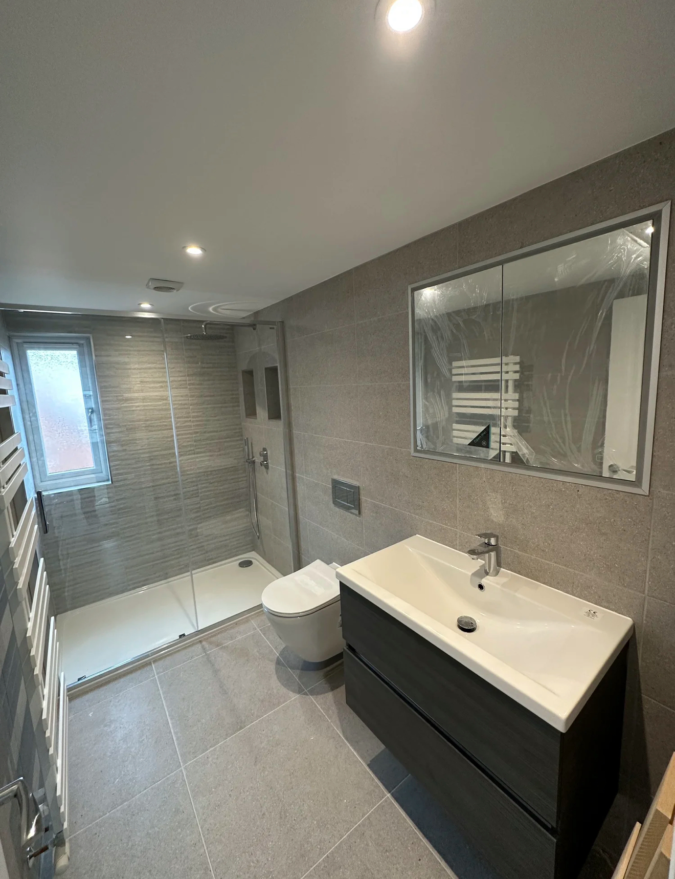 Contemporary grey shower room with floating vanity and large mirror in Reading
