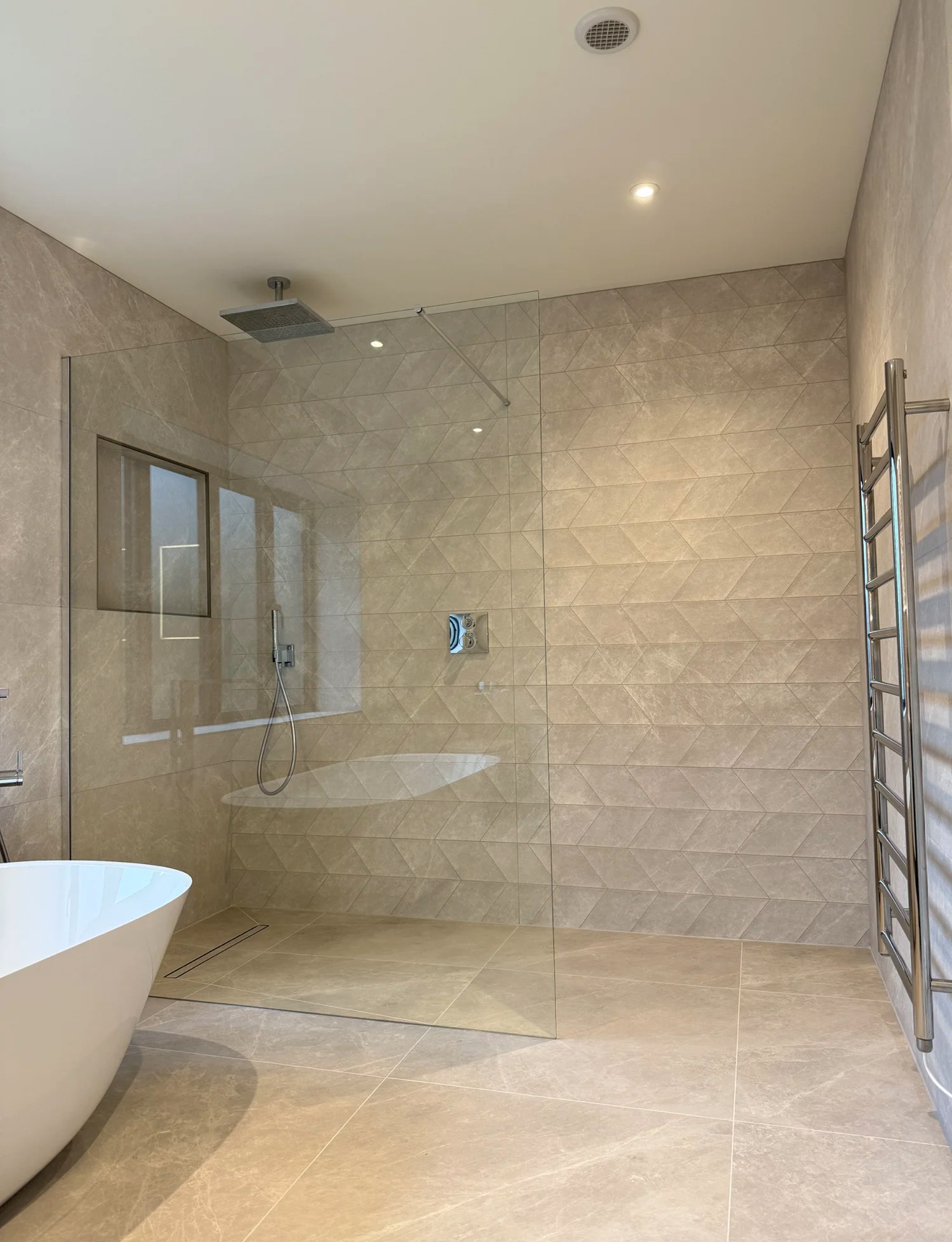 Luxury walk-in wet room with geometric stone tiling and freestanding bath in Reading
