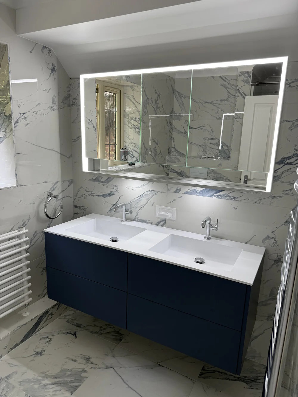 Fitted bathroom with navy vanity, marble walls and LED mirror installed in Reading